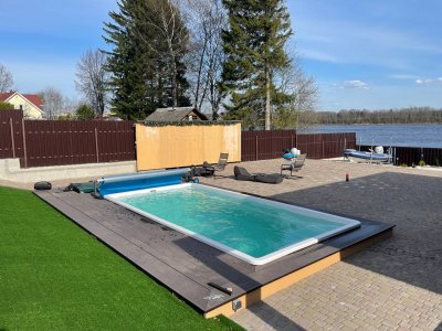 Прямоугольный бассейн с террасой из серо-коричневой композитной доски и зоной отдыха